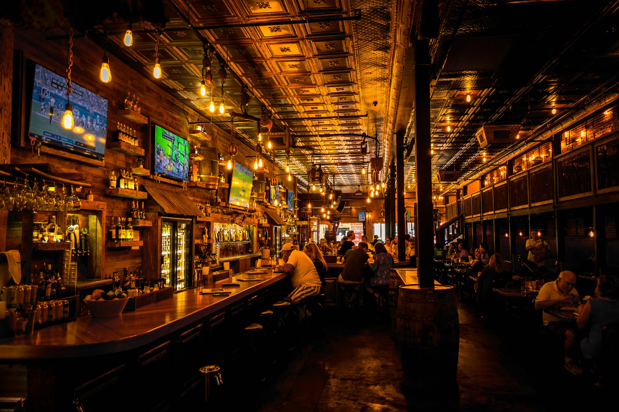 The lively, warmly lit bar inside The Ford Green pub with big screens showing live sport