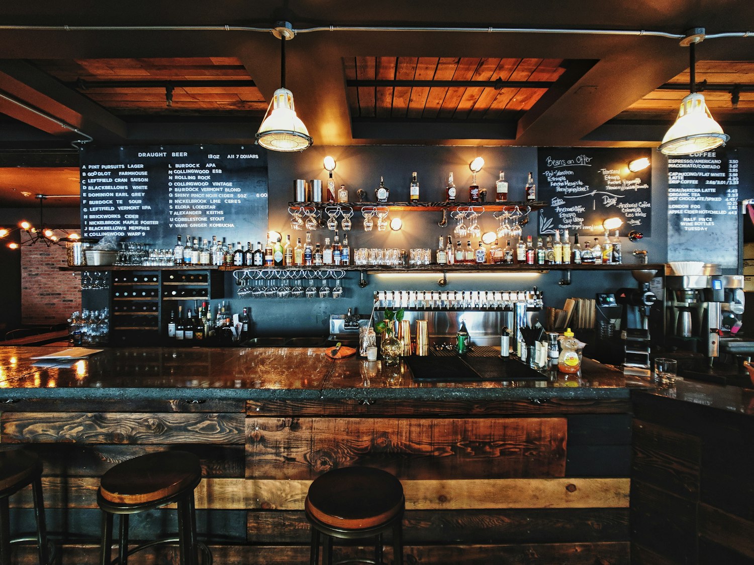 The warm, wood-panelled bar at The Ford Green, lined with bottles and bar stools